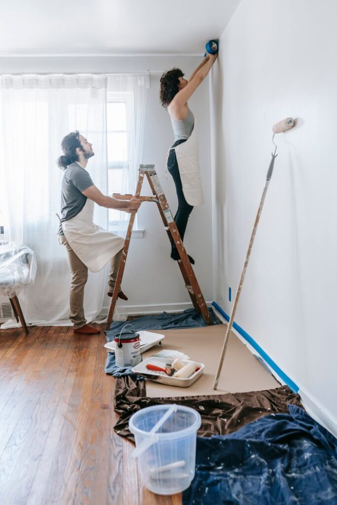 A couple collaborates on painting a room in their new home, focusing on renovation.