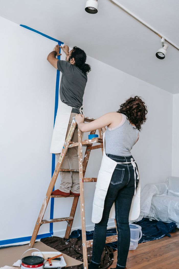 our-story-02 Couple working together on home renovation, painting walls in new apartment.